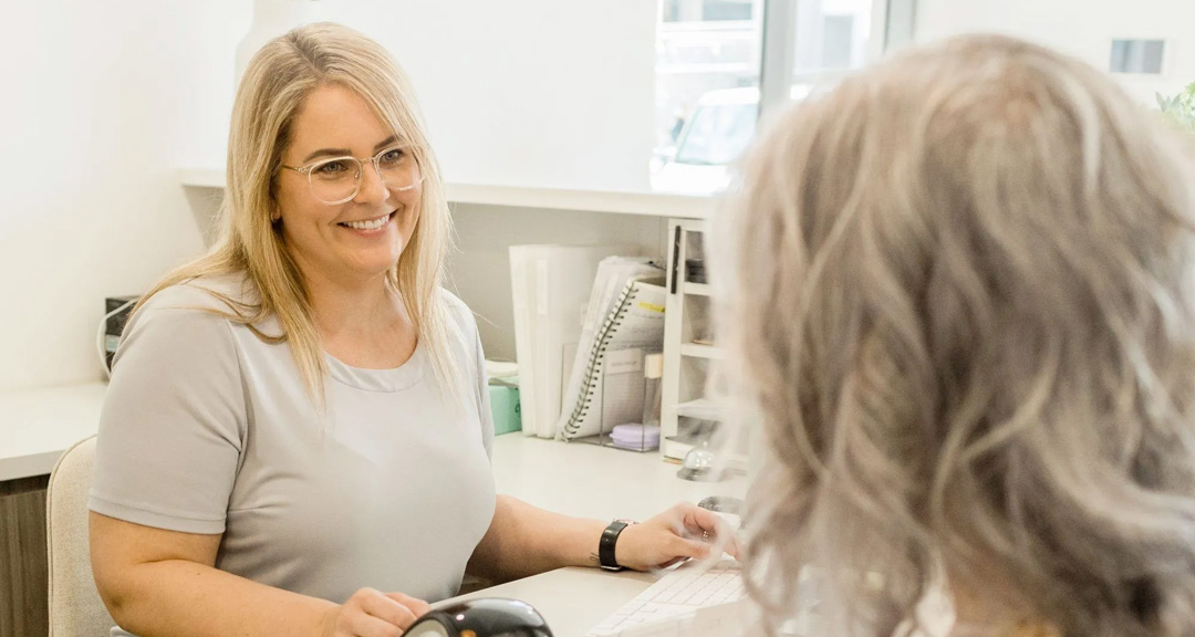 Older patient chatting with our front desk team about dentures Ormeau seniors can book
